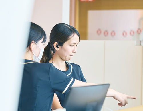 受付で確認し合うスタッフ