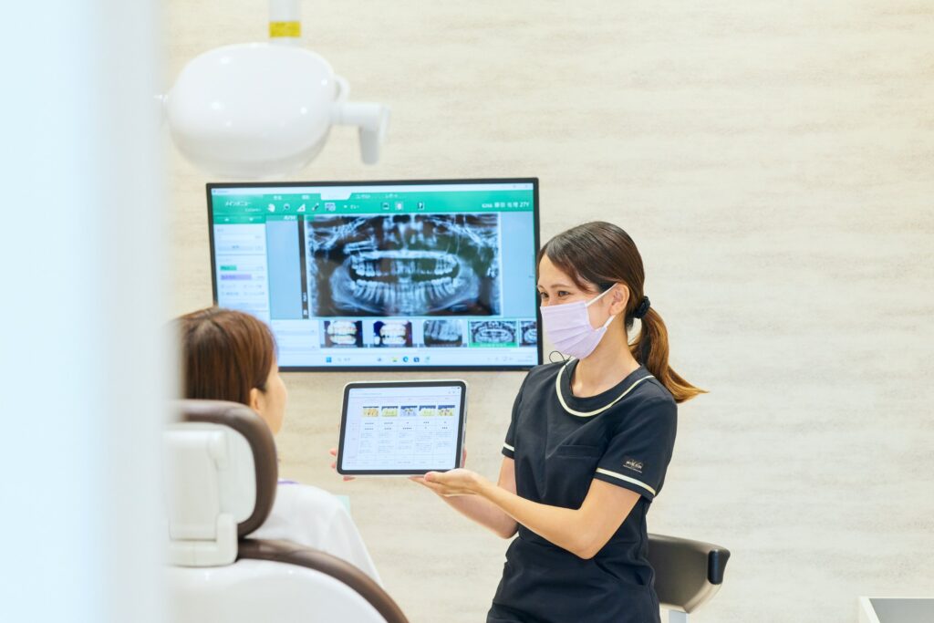 くるみ歯科こども歯科 モニターとタブレットで説明するスタッフ